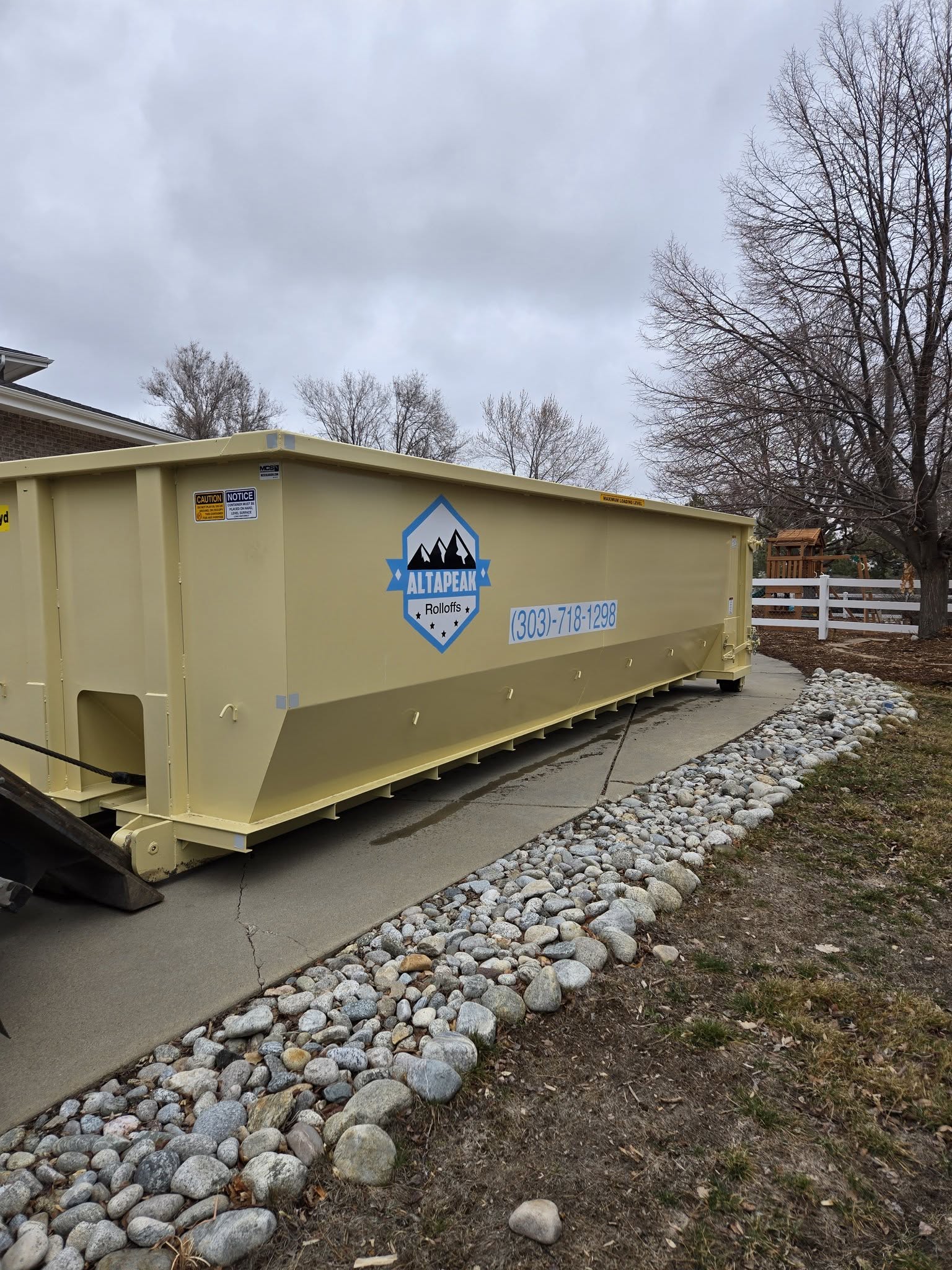 30 yard roll off dumpster on a residential driveway beside a rock garden